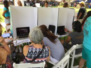 people in a row at the viewing station with headphones watching video of factory farming